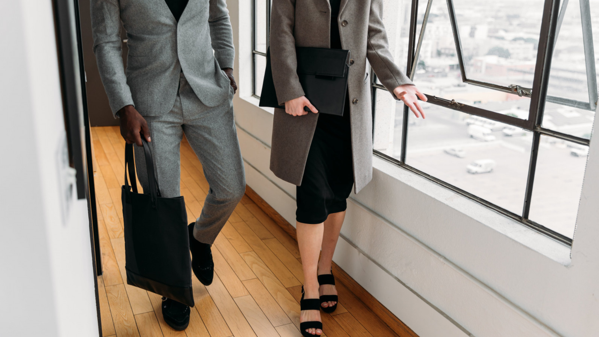 Two business people walking through a hallway in smart suits.